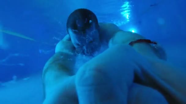 A fiatalember a víz alatt úszik a medencében. — Stock videók