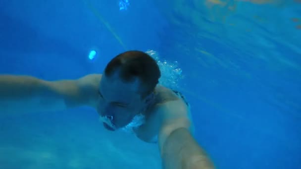 Jongeman met het atletische lichaam zwemt onder water. — Stockvideo