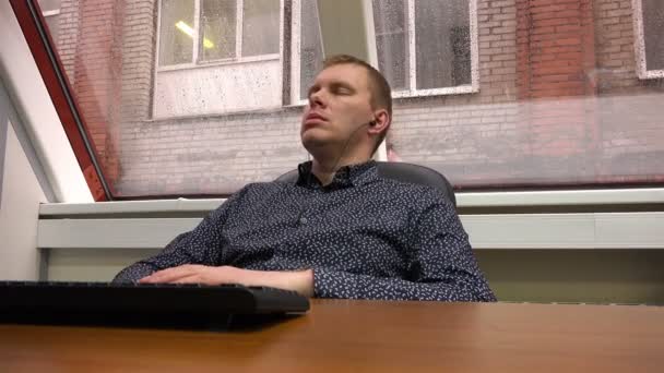 После прослушивания музыки в наушниках молодой человек отдыхает и приступает к работе. — стоковое видео