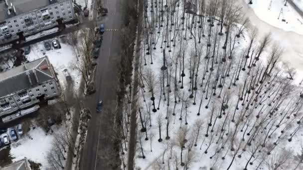 Helikoptervlucht over de weg en grijze huizen met een bevroren meer — Stockvideo