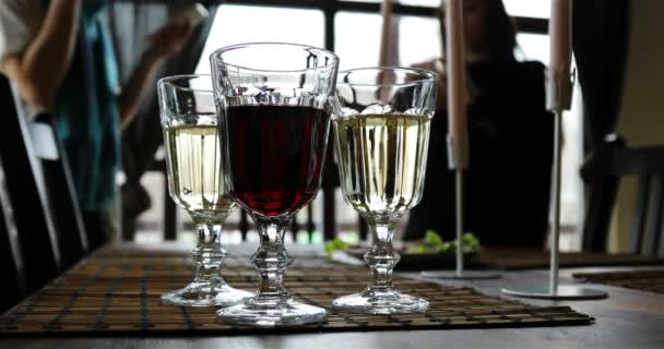 Um copo de vinho tinto e dois copos de vinho branco estão na mesa — Vídeo de Stock
