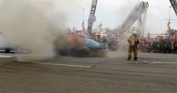 Un pompier avec un réservoir sur le dos met la voiture sur la chaussée — Video