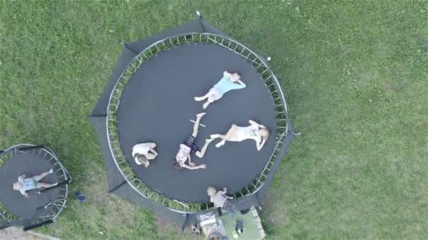 Kinderen ontspannen samen op een trampoline in de tuin — Stockvideo