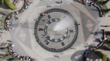 sıcak güneşli bir günde çeşmenin suyuna sıçrayan çocuklar ve yetişkinler