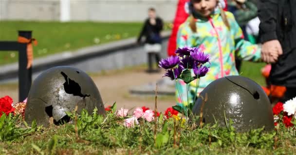 Brutna hjälmar av soldater från militära operationer beströdda med blommor — Stockvideo