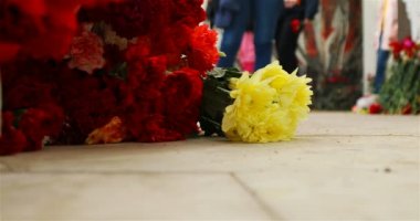 Savaşta ölen askerlerin mezarlarının yanında yerde çiçekler yatıyor.