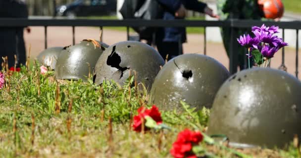 Casques de soldats perforés sur la fosse commune sont disposés comme un souvenir de soldats — Video