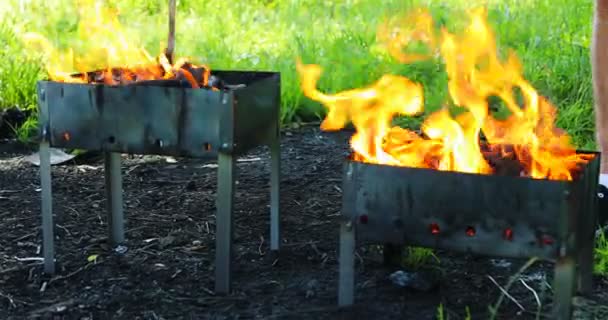 Man met een stok in zijn hand mengt de kolen in de grill — Stockvideo