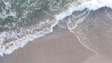 Köpüklü deniz dalgası kumlu bir sahili yıkıyor