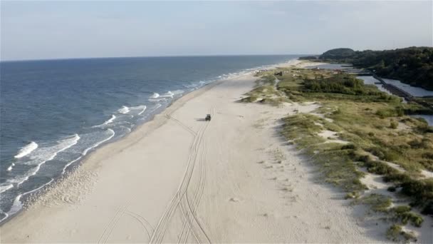 Ein Traktor fährt an einem sauberen Sandstrand entlang und hinterlässt Spuren — Stockvideo