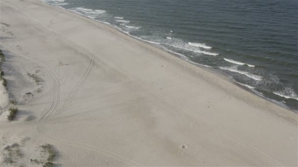 Песчаный пляж у моря со следами автомобилей и туристических ног — стоковое видео