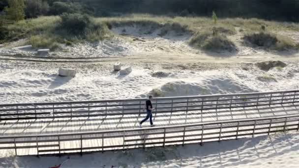 Un vehículo no tripulado vuela alrededor de una persona caminando a lo largo del paseo marítimo — Vídeos de Stock