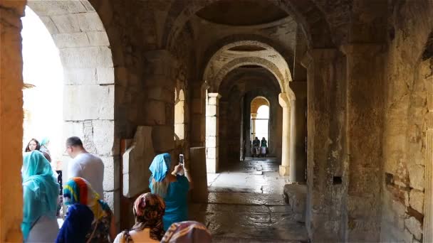 People walk along the ancient buildings of the temple of St. Nicholas the Wonderworker of the IV century — ストック動画