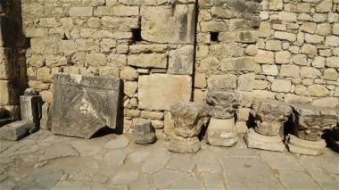 Büyük taş duvarlar oyulmuş taş sütunlar ve levhalarla dolu avlu.