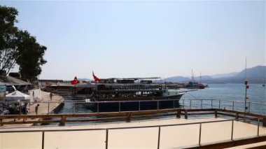 Akdeniz kıyısında yatları ve tekneleri olan iskele ve gökyüzünün dumanında eriyen dağlar.