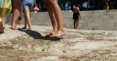 Turistler, kar beyazı kalsit sarkıtları ile süslenmiş teras banyosuna tırmanıyorlar.