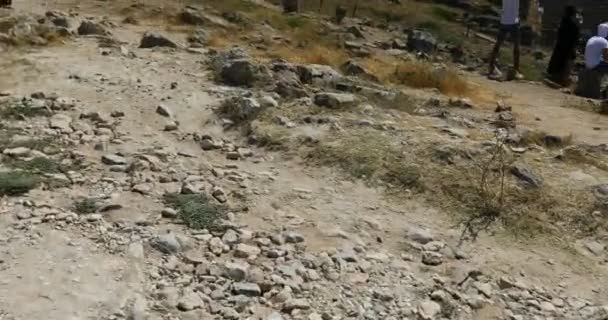 A través del campo, a lo largo de caminos de piedra, los turistas se mueven al anfiteatro antiguo de la ciudad de Hierápolis — Vídeos de Stock