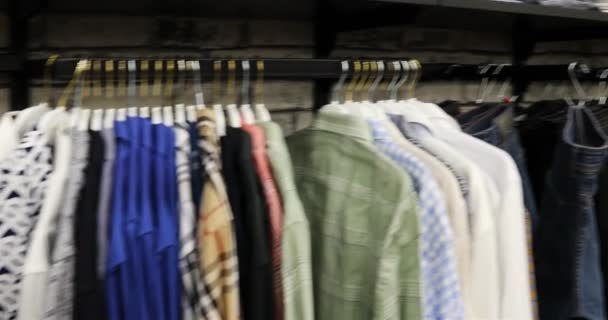 Une large sélection de t-shirts et polos multicolores sur cintres dans le magasin — Video