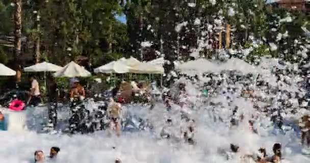 Soapy foam flakes covers swimming people in the pool — Stock Video