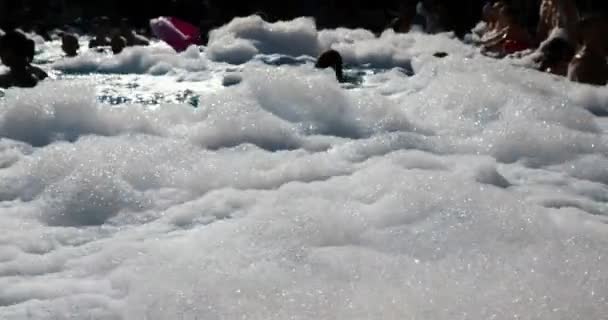 Pessoas nadando na piscina brincar com espuma de sabão em uma festa — Vídeo de Stock