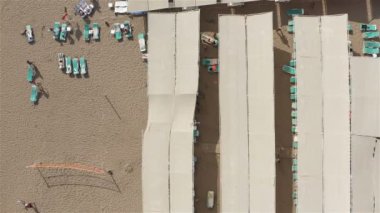 Turistler plaj tatiline hazırlanıyor. Güneşliğin altında oturuyorlar.