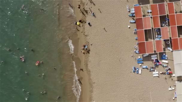 La gente se relaja en una playa de arena junto al mar y tomar el sol bajo el sol de verano — Vídeo de stock