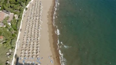 Şemsiyelerin altında turistlerin dinlenme yerleri ve denizin kumlu sahillerinde güneşten korunan barınaklar.