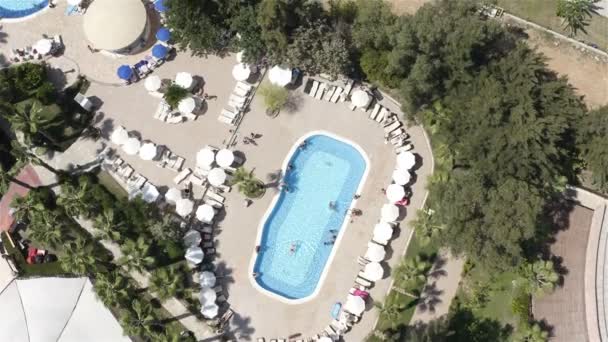 En el territorio del hotel alrededor de la piscina hay tumbonas bajo sombrillas para los turistas — Vídeo de stock