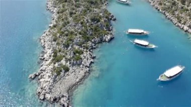 Küçük insan grupları turistik yatların yakınındaki mavi deniz suyunda yüzüyor. Daha hızlı ateş et.