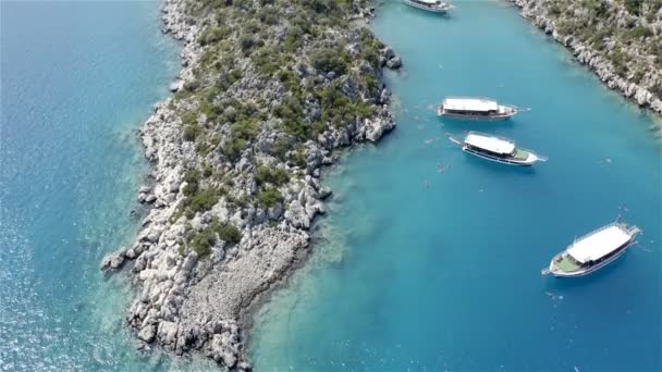 Trzy białe jachty z turystami na pokładzie zacumowane w pobliżu kamiennych wysp — Wideo stockowe