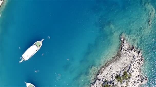 2隻のヨットが地中海の青いラグーンに錨を下ろしました。開放的な海で泳ぐ観光客 — ストック動画