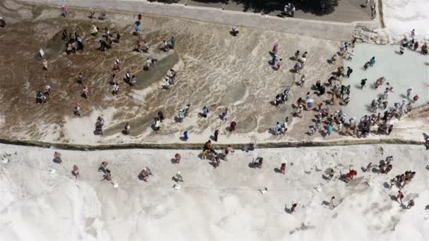 Terrazas blancas y piscinas con aguas termales que los turistas disfrutan en la ladera de las estalactitas — Vídeo de stock