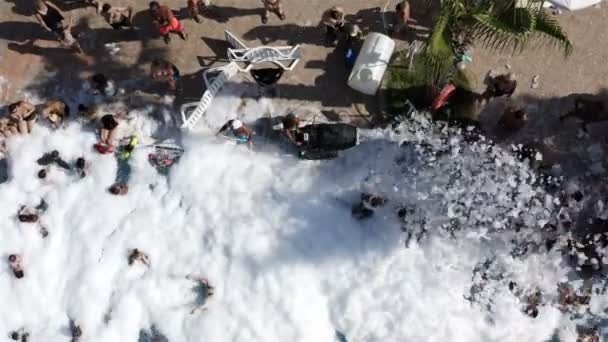 Animator van de generator sprays zeepschuim over het zwembad douchen toeristen met witte granen — Stockvideo