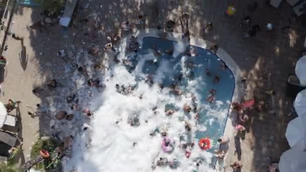 Los turistas bailan y se bañan en la piscina de espuma en el lugar. Tiro superior — Vídeo de stock