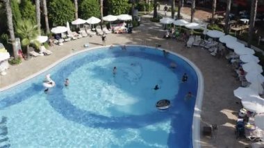 Lastik bir çemberin üzerinden havuza atlayan bir kız.