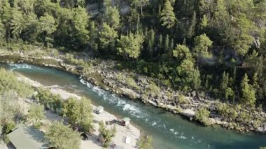 Dar bir vadide, dağlardan akan bir nehir. Dik kıyıları ve kaya parçalarıyla dolu kayalık bir yatak.