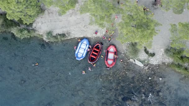 После сплава по горной реке туристы вытаскивают резиновые надувные лодки на берег — стоковое видео