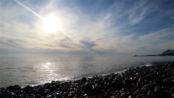 波は明るい太陽の光の中で石の海岸を洗い — ストック動画