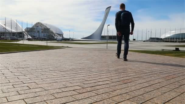 Un hombre camina hacia el tazón de la llama olímpica en el Parque Olímpico de Sochi — Vídeos de Stock