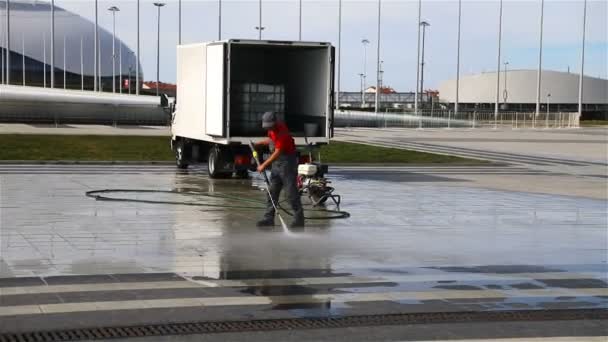 Zaměstnanec, který čistí dlaždice silným tlakem vody — Stock video