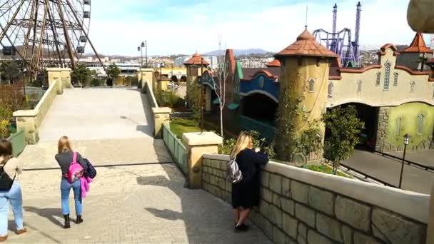 Eine Steinstraße über die Brücke führt Touristen zum Riesenrad im Sotschi-Park — Stockvideo