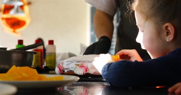 Девушка кладет фрукты на края торта — стоковое видео