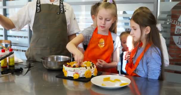Дети украшают торт кусочками шоколада — стоковое видео