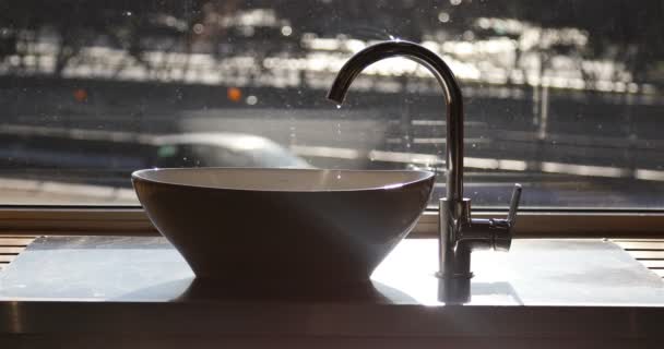 Water drips from the shiny tap into the white sink — Stock Video