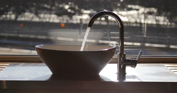 En ström av vatten rinner från kranen in i diskhon — Stockvideo