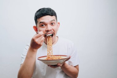 Genç bir adam, yüzünde heyecan ve neşeyle bir kase eriştenin tadını çıkarır..