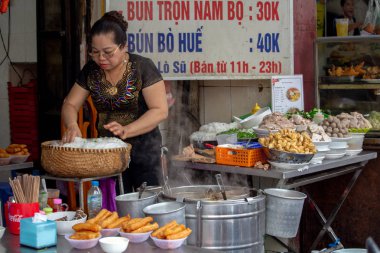 Hanoi, Vietnam - 16 Mart 2018: Merkez Hanoi bir sokak gıda ahır içinde çalışan kadın