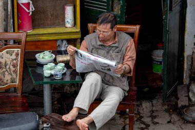 Hanoi, Vietnam - 16 Mart 2018: sokak oturan ve bir gazete okuyor yerel bir adam