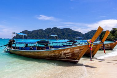 Koh Phi Phi, Tayland - 7 Mayıs 2018: Duru turkuaz suları ile kumlu bir plaj üzerinde uzun kuyruk yerel tekneler demirli