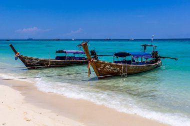 Koh Phi Phi, Tayland - 7 Mayıs 2018: Duru turkuaz suları ile kumlu bir plaj üzerinde uzun kuyruk yerel tekneler demirli